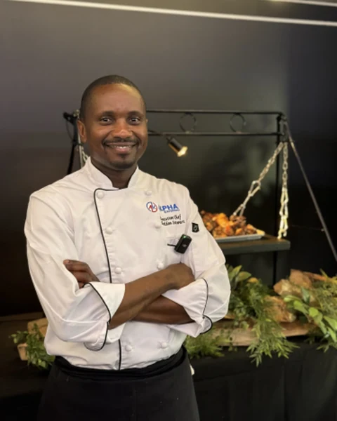 Sheldon Stewart in an Alpha Katering chef’s jacket in front of a carved fish display