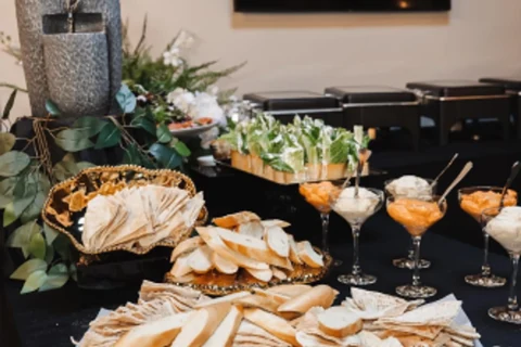 A buffet spread of dips, pita and salads on black linen