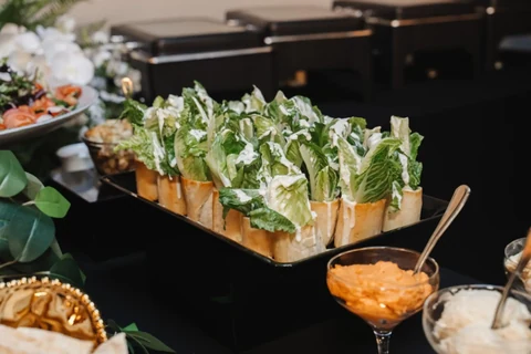 Rows of green appetiser cups arranged on a dark serving tray