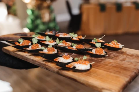 Salmon canapés with microgreens lined up on a live-edge serving board