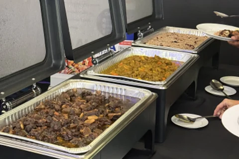 Rows of chafing dishes holding rice and stewed meat, plated up for a large service