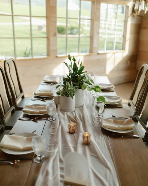 A wedding table laid with glassware, linen and fresh greenery