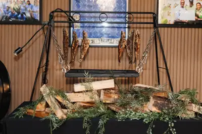 A fish display hung from a black frame above firewood and fresh rosemary