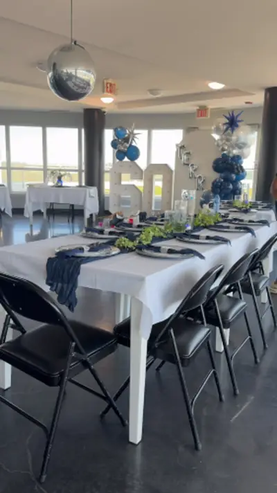 A long banquet table set with blue and silver balloons