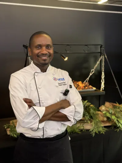 An Alpha Katering chef in whites standing in front of a carved fish display