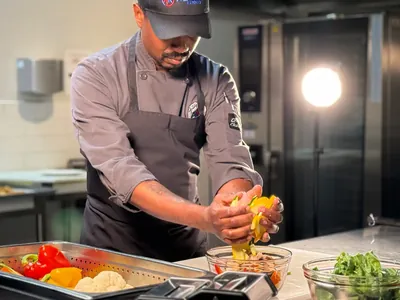 An Alpha Katering chef plating a dish on the kitchen pass